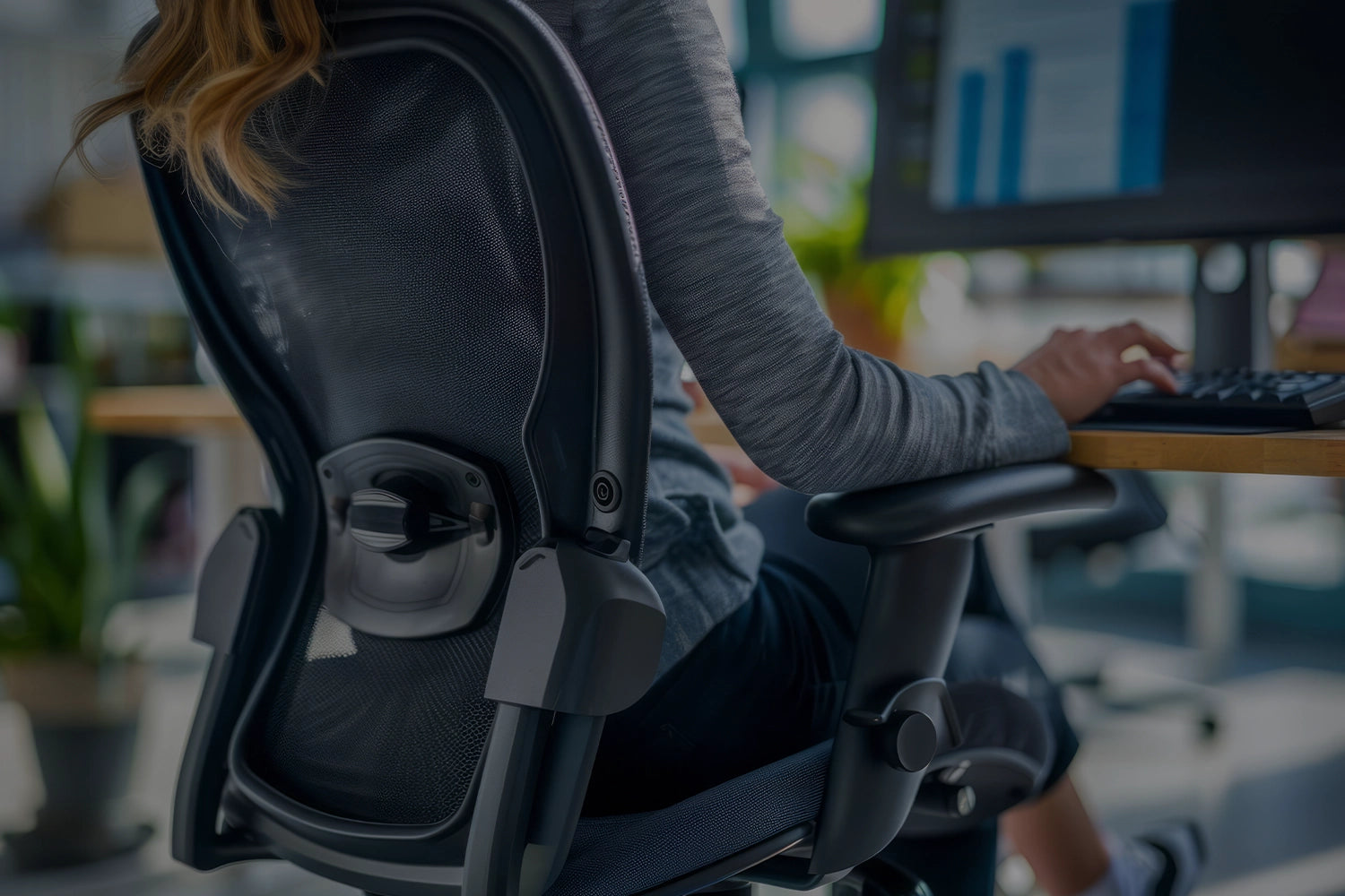 Femme assise sur son siège ergonomique devant son bureau assis-debout