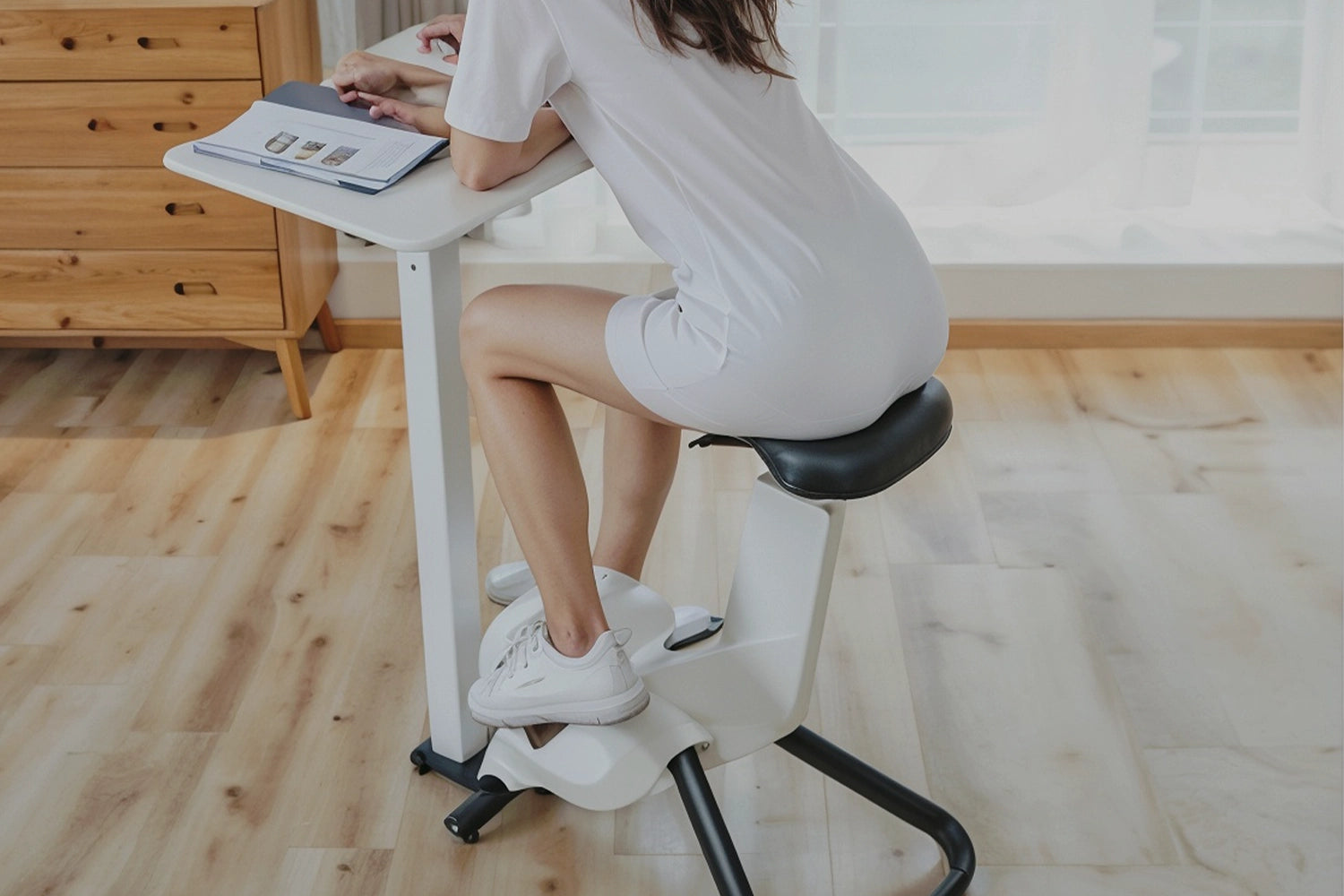 Femme en train de feuilleté un magazine sur un vélo de bureau blanc